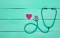 Stethoscope and heart on a blue wooden table. Cardiology equipment for diagnosing cardiovascular diseases. Top view.