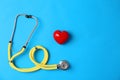 Stethoscope and heart on color background, top view. Medical equipment