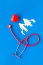 Stethoscope, heart and paper figure for family doctor set on blue background top view
