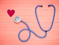 Stethoscope and heart on pastel pink wooden table. Cardiology equipment for diagnosing cardiovascular diseases. Top view. Flat lay Royalty Free Stock Photo