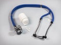 Stethoscope and jar of white pills on blue gray background. Medical and cardio heart health concept Royalty Free Stock Photo