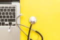 Stethoscope keyboard laptop computer isolated on yellow background. Modern medical Information technology and sofware