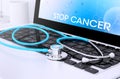 stethoscope on laptop keyboard with screen showing stop cancer