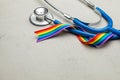 Stethoscope and LGBT rainbow ribbon pride tape symbol. Medical support after sex reassignment surgery. Grey background