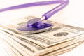 A stethoscope lies on a bundle of money and pills on a light wooden background. The concept of expensive medicine, medical insuran Royalty Free Stock Photo