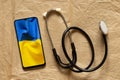 The stethoscope lies next to the phone and a photo of the national flag of Ukraine is yellow and blue. Doctors during the war,