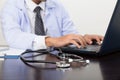 stethoscope is lying on the table near male doctor typing on lap Royalty Free Stock Photo