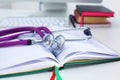 Stethoscope lying on a table an open book Royalty Free Stock Photo