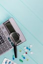 Stethoscope and magnifier over a calculator symbol for health care costs or medical insurance.