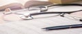 Stethoscope, magnifier, pen and books lay on cardiograms on table Royalty Free Stock Photo