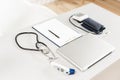 Stethoscope, measuring blood pressure and laptop on wooden desk for analysis of medical results. Royalty Free Stock Photo