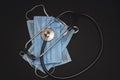 Stethoscope and medical respirator disposable mask for protection against viruses on a black background Royalty Free Stock Photo