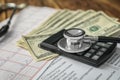 Stethoscope with money and calculator, closeup. Health care concept