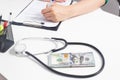 A stethoscope and money dollars lie on a white medical table at the doctor`s. Concept of bribery in medicine and sale of Royalty Free Stock Photo