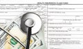 Stethoscope with money on health insurance claim form. Top view Royalty Free Stock Photo