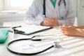 Stethoscope next to hand of doctor reassuring her female patient. Medical ethics and trust concept Royalty Free Stock Photo