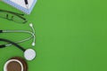 Stethoscope with notebook ,pen, coffee ,white paper ,glasses, bottle of medicine on green background,Medical background concept Royalty Free Stock Photo