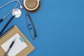 Stethoscope with notebook ,pen, white paper ,coffee cup,glasses, on blue background,Medical background concept Royalty Free Stock Photo