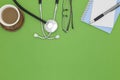 Stethoscope with notebook ,pen, white paper ,coffee cup,glasses, on green background,Medical background concept. Royalty Free Stock Photo