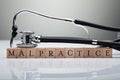 Stethoscope Over Malpractice Wooden Block