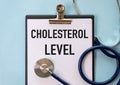 Stethoscope and paper note with text CHOLESTEROL LEVEL. Health concept.