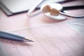 Stethoscope with pen glasses, magnifier and cardiogram and other medicine equipment lay on a table Royalty Free Stock Photo