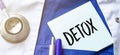 Stethoscope, pens and note with text DETOX on the doctor uniform Royalty Free Stock Photo