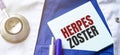 Stethoscope, pens and note with text herpes zoster on the doctor uniform Royalty Free Stock Photo