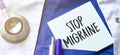 Stethoscope, pens and note with text stop migraine on the doctor uniform Royalty Free Stock Photo