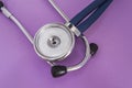 Stethoscope or phonendoscope lying on a purple background big head diaphragm, plastic disc upwards near the earpieces closeup Royalty Free Stock Photo