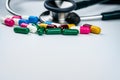 Stethoscope with pile of antibiotic capsule pills on white background. Antimicrobial drug resistance and overuse. Medical