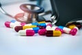 Stethoscope with pile of colorful antibiotic capsule pills on white table with drug tray. Antimicrobial drug resistance