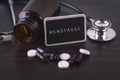 Stethoscope, pill bottle, Various pills, capsules and MENOPAUSE on wooden background