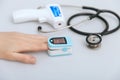 Stethoscope, pulse oximeter and thermometer gun on white background. Phonendoscope. Infrared isometric thermometer gun