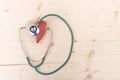 Stethoscope and red fabric heart lying on wooden table. Healthca
