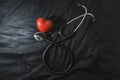 Stethoscope and red heart figure on black background, indoor