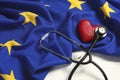 Stethoscope, red heart and flag of European Union on white wooden table Royalty Free Stock Photo