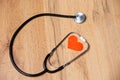 Stethoscope with red heart shape inside, on wooden background. Health and medicine symbol. Heartbeat for flyers, poster, web, Royalty Free Stock Photo