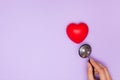 Woman doctor listens to work heart with stethoscope on purple background, flat lay.