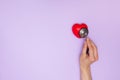 Woman doctor listens to work heart with stethoscope on purple background, flat lay.