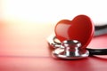 A stethoscope and red shape heart laying on top of a red table