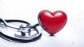 A stethoscope rests beside a healthy red heart on a white background