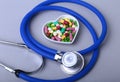 Stethoscope, RX prescription and colorful assortment pills and capsules on plate.