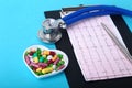 Stethoscope, RX prescription and colorful assortment pills and capsules on plate.