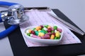 Stethoscope, RX prescription and colorful assortment pills and capsules on plate.