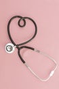 Stethoscope in the shape of heart on pink background Royalty Free Stock Photo