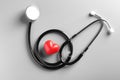 Stethoscope and small red heart on gray background. Royalty Free Stock Photo