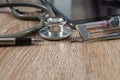 Stethoscope with syringe, pen, tablet and dental tools on wooden table Royalty Free Stock Photo