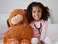 Stethoscope, teddy bear and girl with a child her stuffed animal with a smile in her house. Portrait of happy female kid Royalty Free Stock Photo