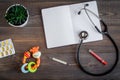 Stethoscope, thermometer, notebook on children`s doctor office desk background top view mockup Royalty Free Stock Photo